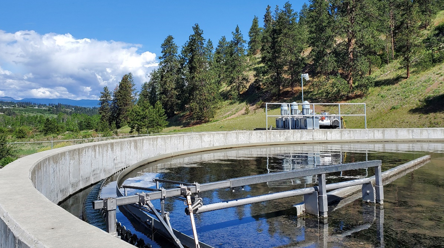 Photo of a clarifier basin near a beautiful green forest representing Carollo's greenhouse gas emissions services