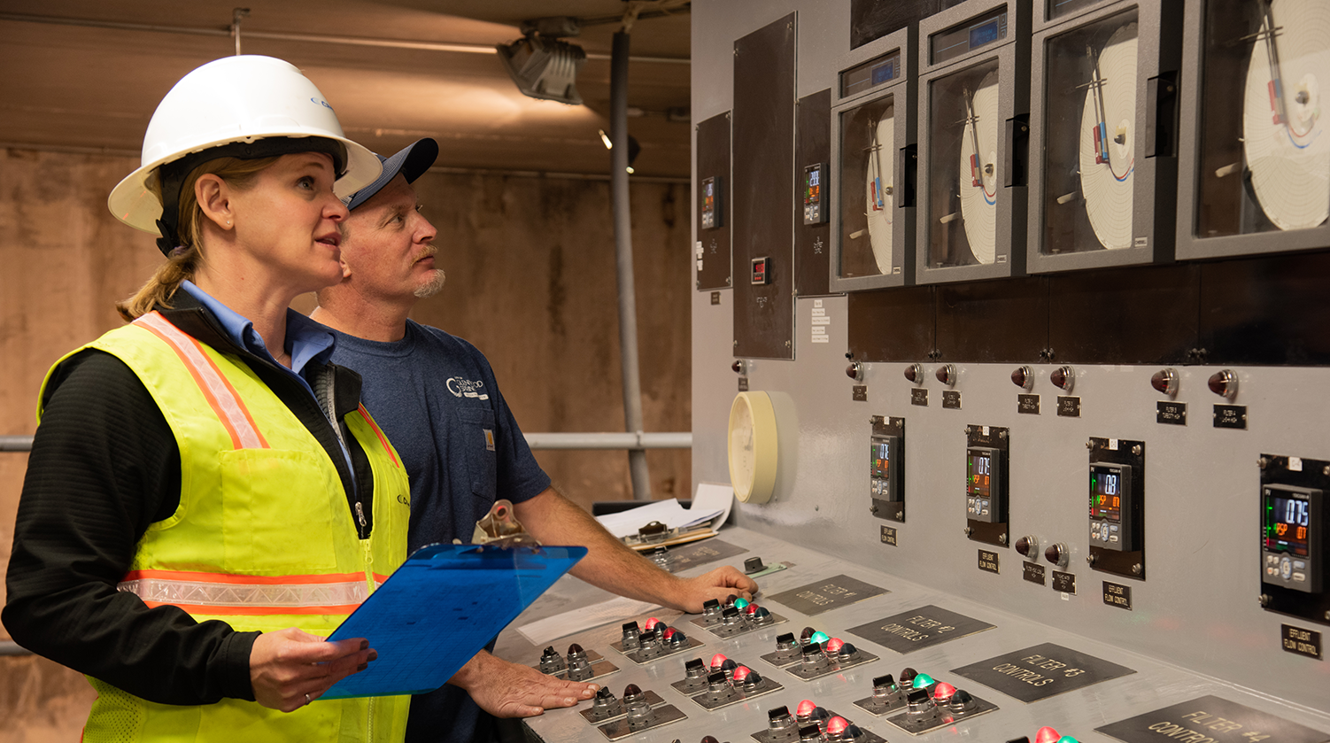Two Carollo operators stand at SCADA monitoring equipment